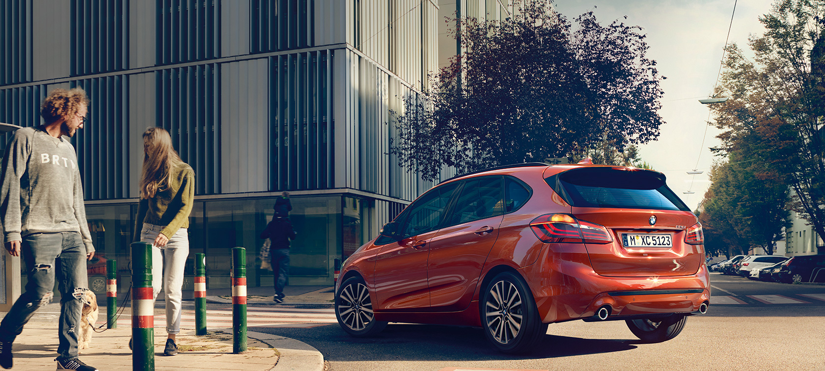 BMW 2 Series Active Tourer 220i F45 Sunset Orange metallic three-quarter rear view driving on the road 