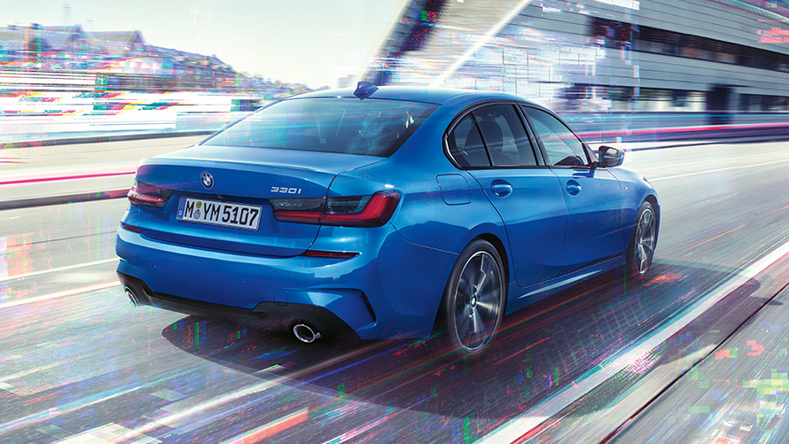 Three-quarter rear shot of the BMW 3 Series Sedan (G20) at day in front of an urban setting. 